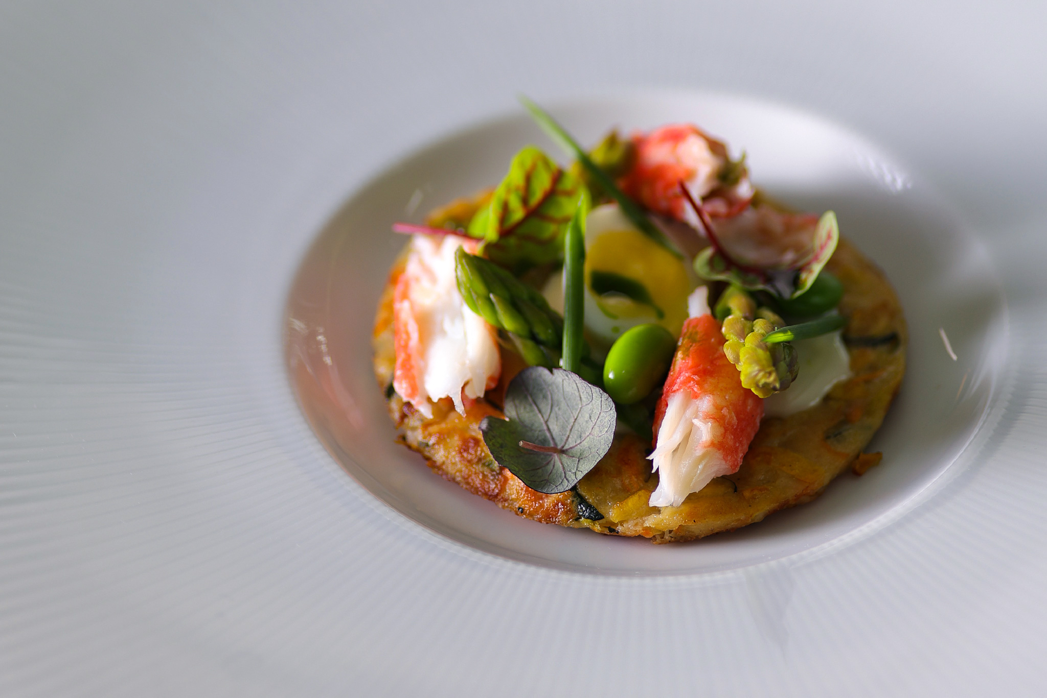 Rösti with Stracciatella cheese, Kamchatka crab, quail egg, and green vegetables